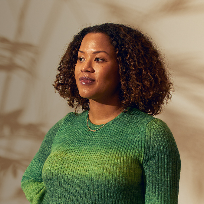 Sydney de pie en el interior y mirando hacia su derecha con una gesto que transmite seguridad.