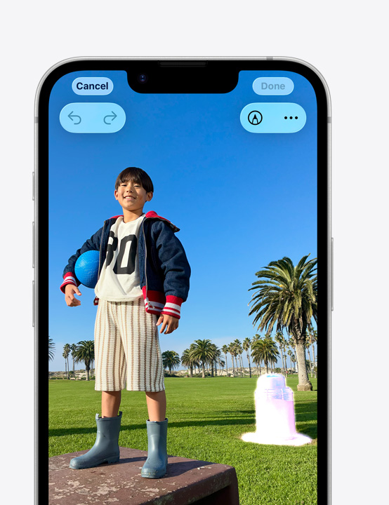 iPhone screen, photo of person smiling on a park ledge, showing how to remove a trash can in the background with the Clean Up tool
