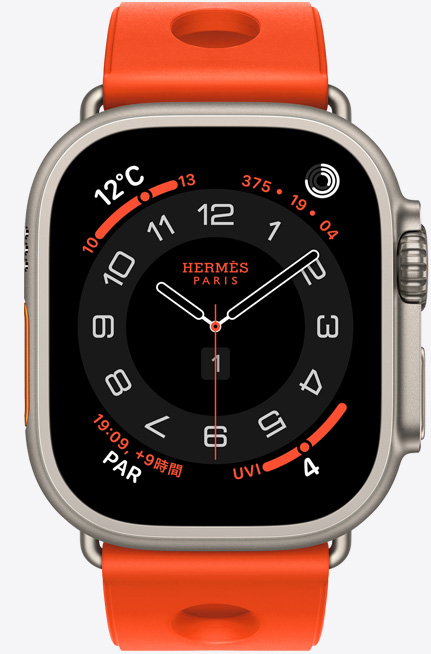 ナチュラルチタニウムケースのApple Watch Hermès Ultra 3。アナログデザインのCirculaire文字盤に、時針、分針、秒針と、天気、アクティビティリング、パリ時間、UV指数のコンプリケーションが表示されている。右側面の外観には、Digital Crown、少し突き出たサイドボタンが見えている。ラバー素材を成形し、中央に円形のカットアウトをあしらった、オランジュ・ネオン（ブライトオレンジ）のスキュブHダイビングストラップが付いている