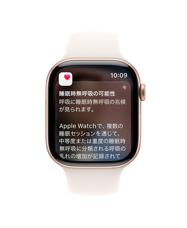 ローズゴールドアルミニウムケースのApple Watch Series 11。画面に睡眠時無呼吸の通知が展開されている。右側面の外観、Digital Crown、ライトブラッシュのスポーツバンド