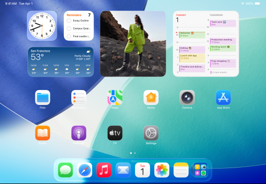 iPad, three models, landscape orientation, with center model in front of two others, Apple Pencil magnetically attached to top of center model, center screen showing the Home Screen featuring colorful app icons with Liquid Glass effect, left screen showing the Preview app, right screen showing Home Screen with files fanning out from the dock
