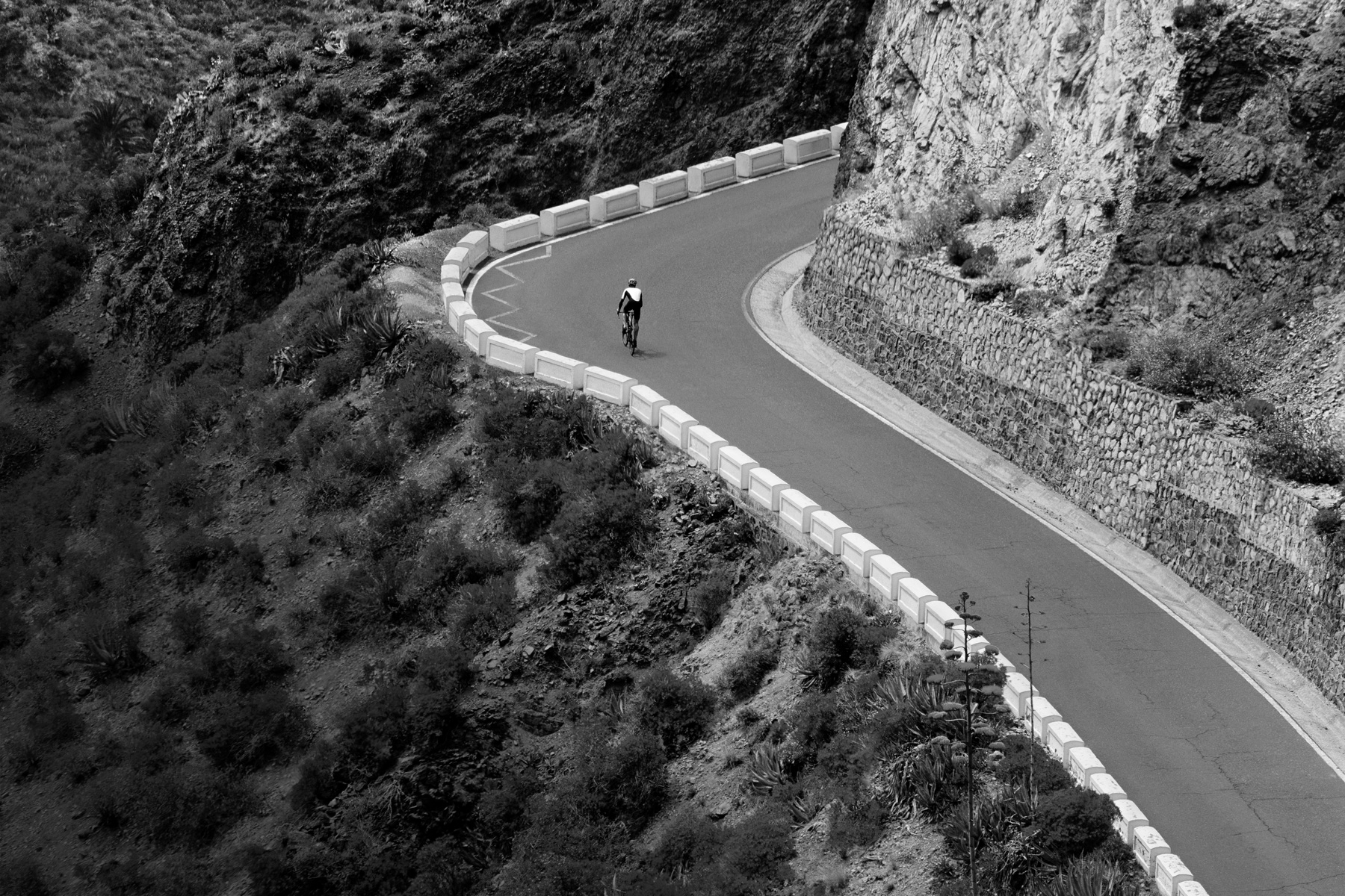 A cyclist rides up a mountain road
