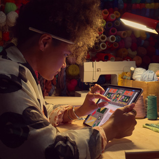 Une personne assise à un bureau utilise deux doigts sur l’écran d’un iPad pour agrandir une image.