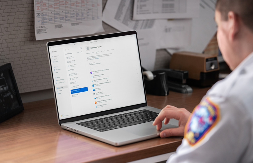 A fire department leader uses a MacBook with Apple Business Essentials open on the screen while seated in an office