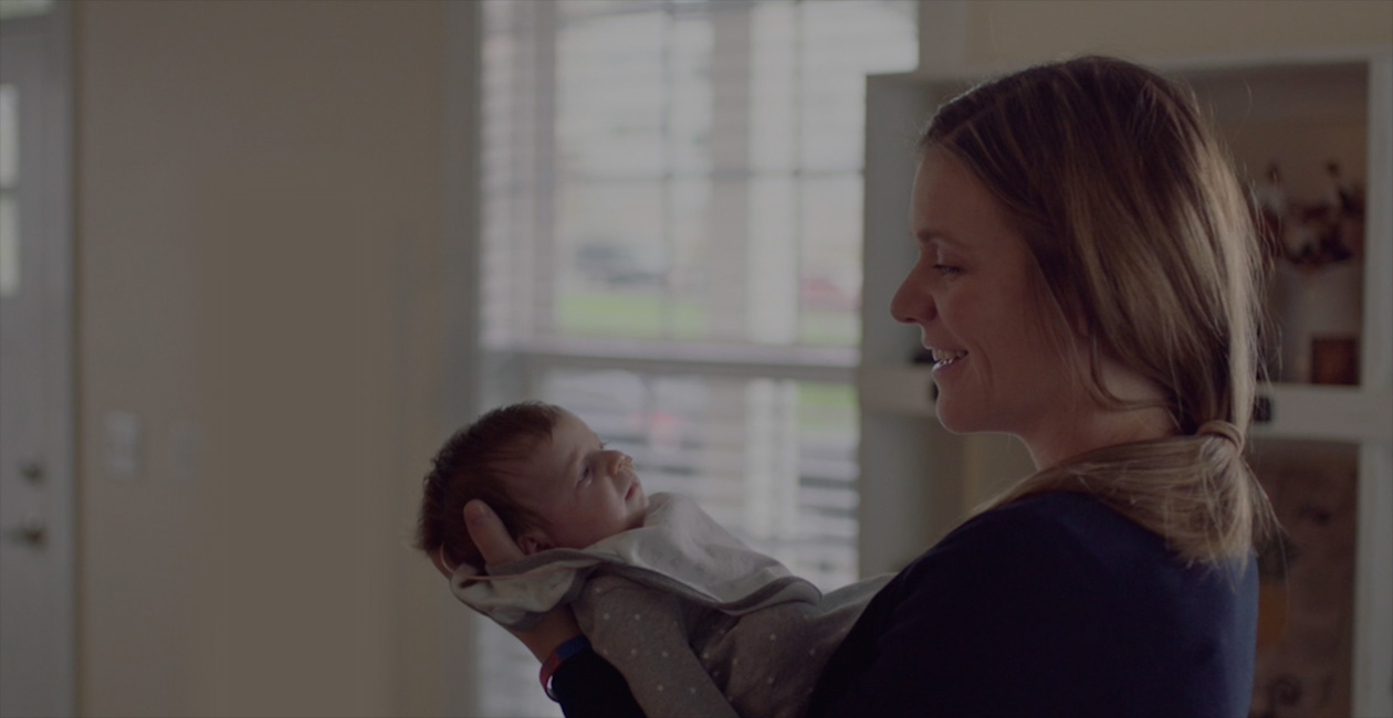 Một người mẹ đang mỉm cười với đứa con mới sinh.