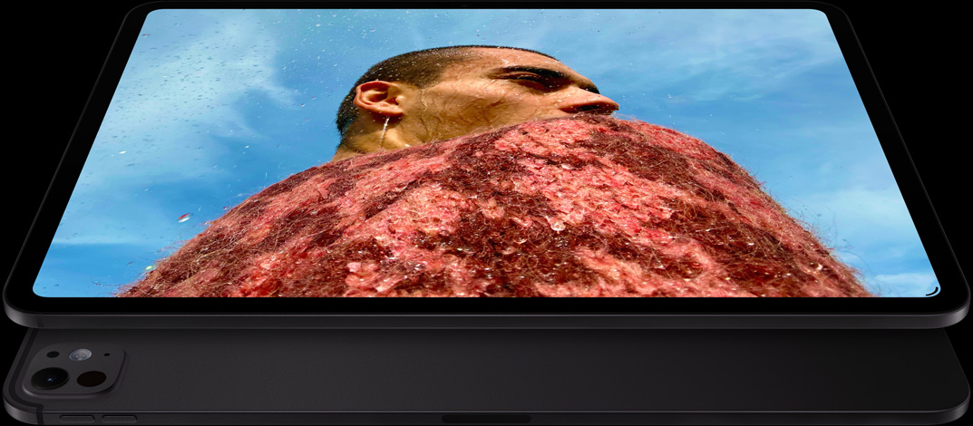 iPad Pro, front side exterior, landscape orientation, space black colour, rounded corners, black display bezel, display showing a photo of a man in a red sweater under a blue sky, underneath, another iPad Pro, back exterior, landscape orientation, space black colour, pro camera system, volume-up button, volume-down button