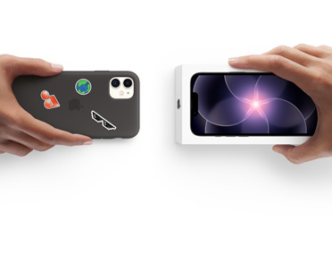 Two hands side by side, hand holding iPhone 11 in Silicone Case with stickers on back exterior, trade-in, with hand holding new iPhone 17e box