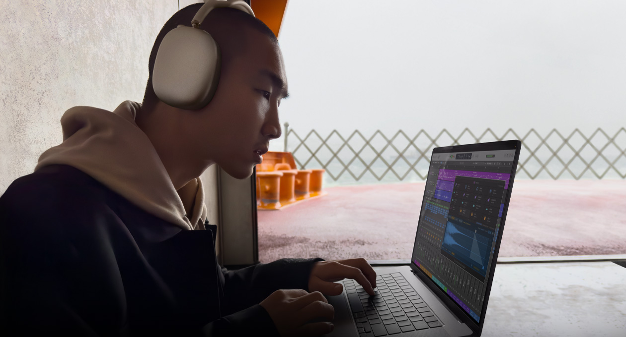 Side profile of a person wearing AirPods Max using Logic Pro on a MacBook Pro 16″