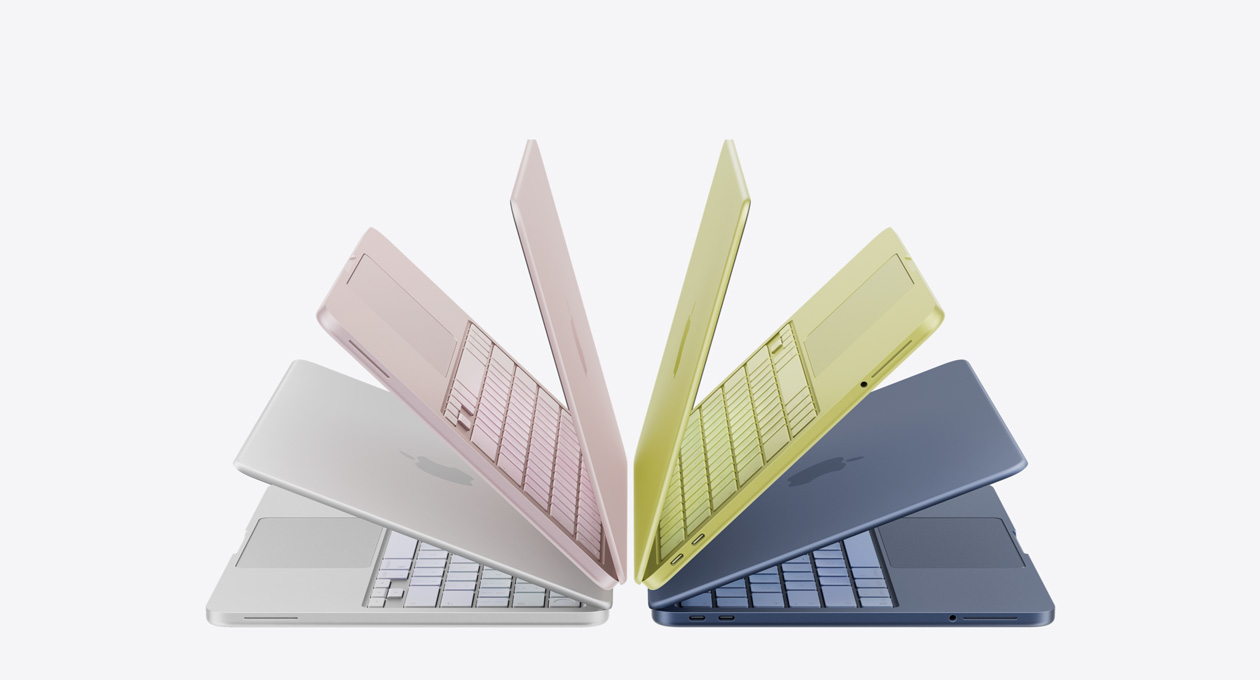 MacBook Neo laptops in silver, blush, citrus and indigo colours, slightly open and arranged in an arch formation