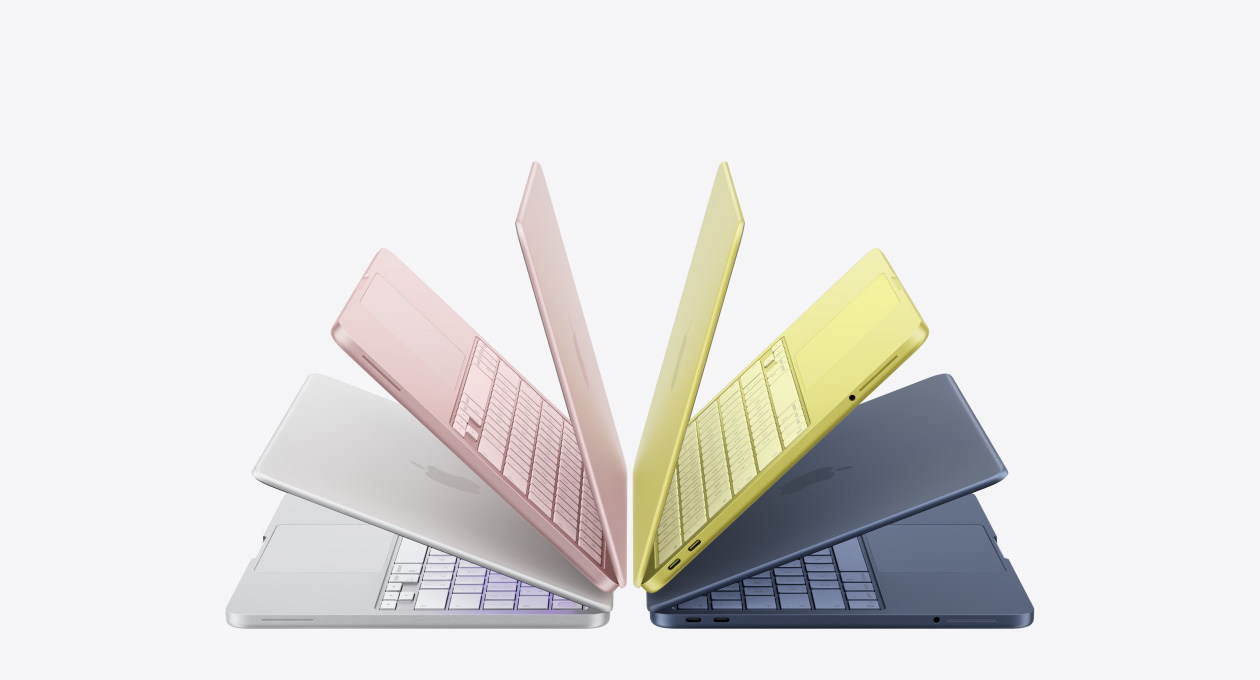 MacBook Neo laptops in silver, blush, citrus and indigo colours, slightly open and arranged in an arch formation