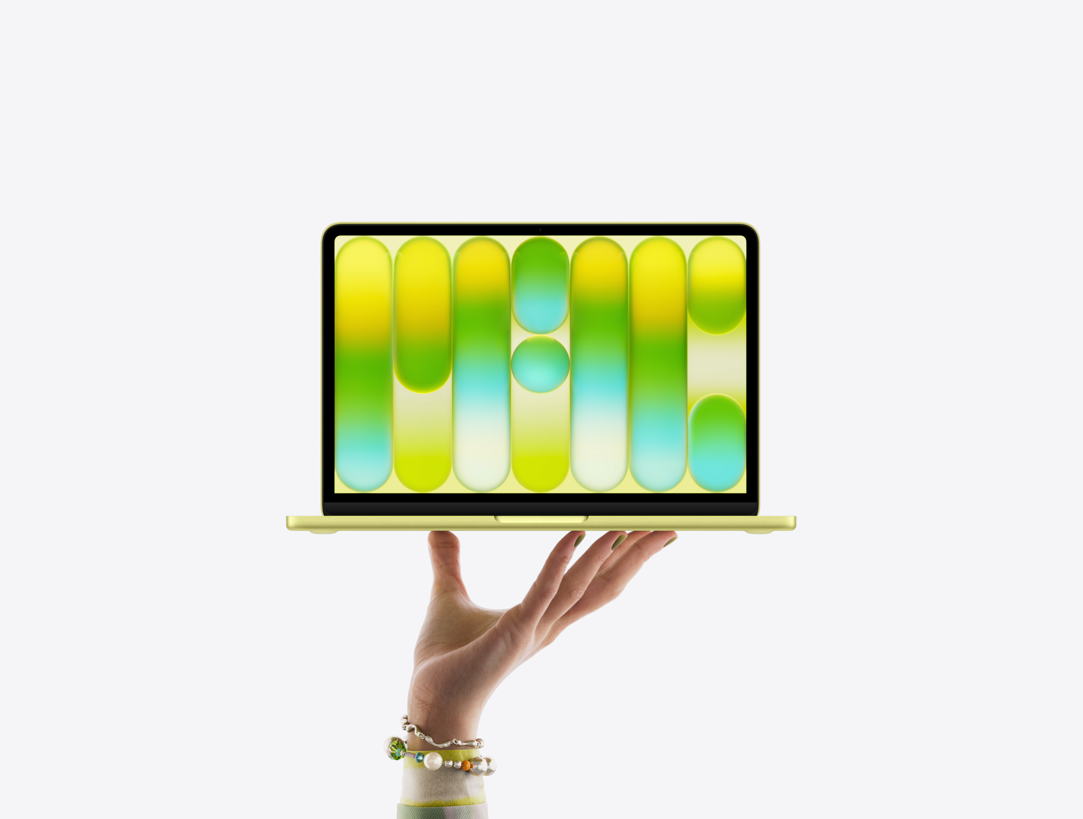 MacBook Neo in citrus colour, balanced on fingertips of open hand, screen displaying colourful abstract pattern