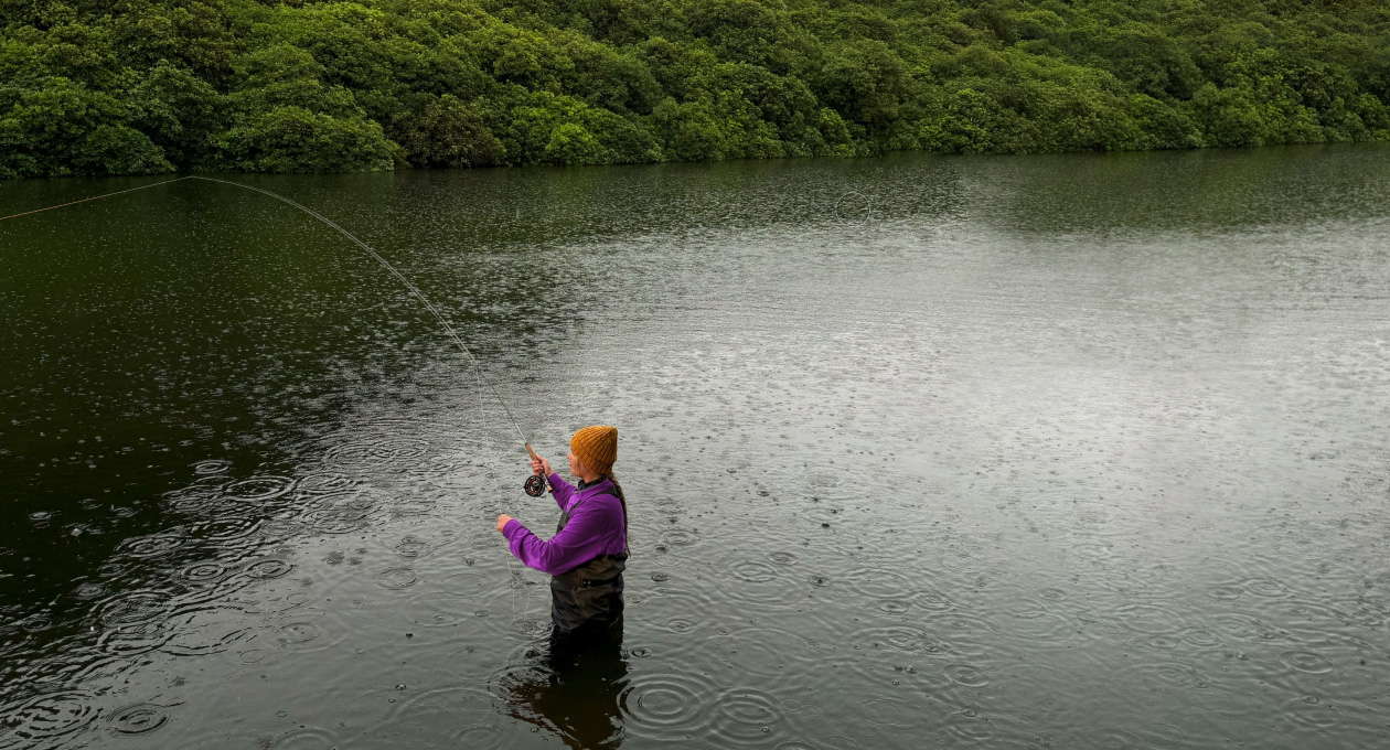 Photo of a woman fly fishing in a lake, Pixelmator Pro tool removing unwanted object in the background being highlighted in yellow