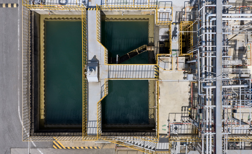 Luchtfoto van industriële waterzuiveringstanks die in een rasterpatroon zijn opgesteld.