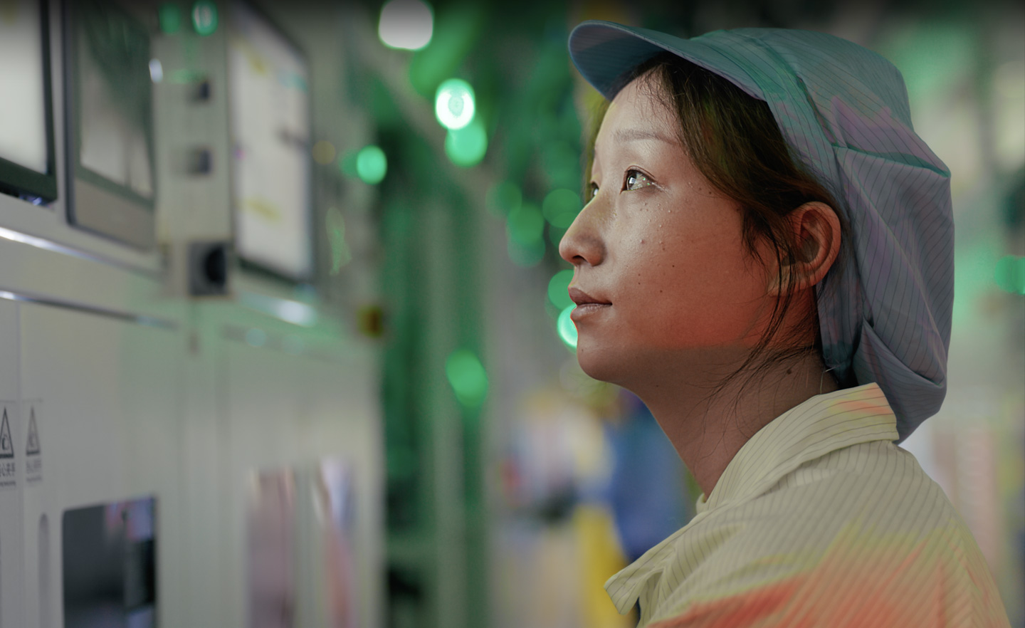 Een medewerker in uniform werkt in een fabriek die onderdelen produceert, bij groen licht
