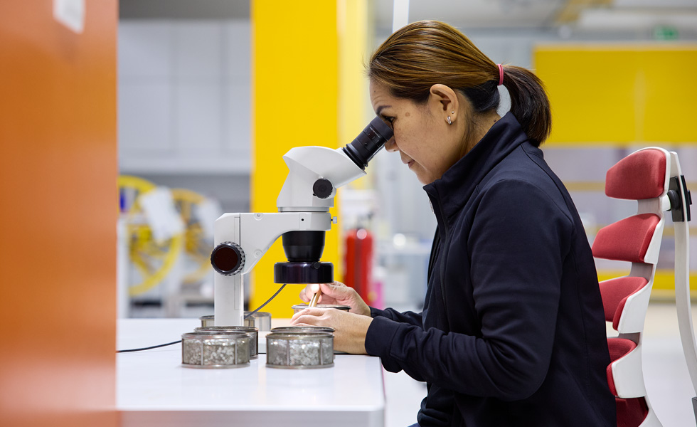 Een technicus inspecteert assemblagecomponenten met een stereoscoop