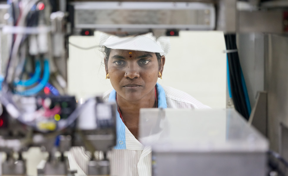 Een medewerker in de robotica-afdeling houdt een werkdevice vast terwijl hij of zij naar een robotica-machine kijkt