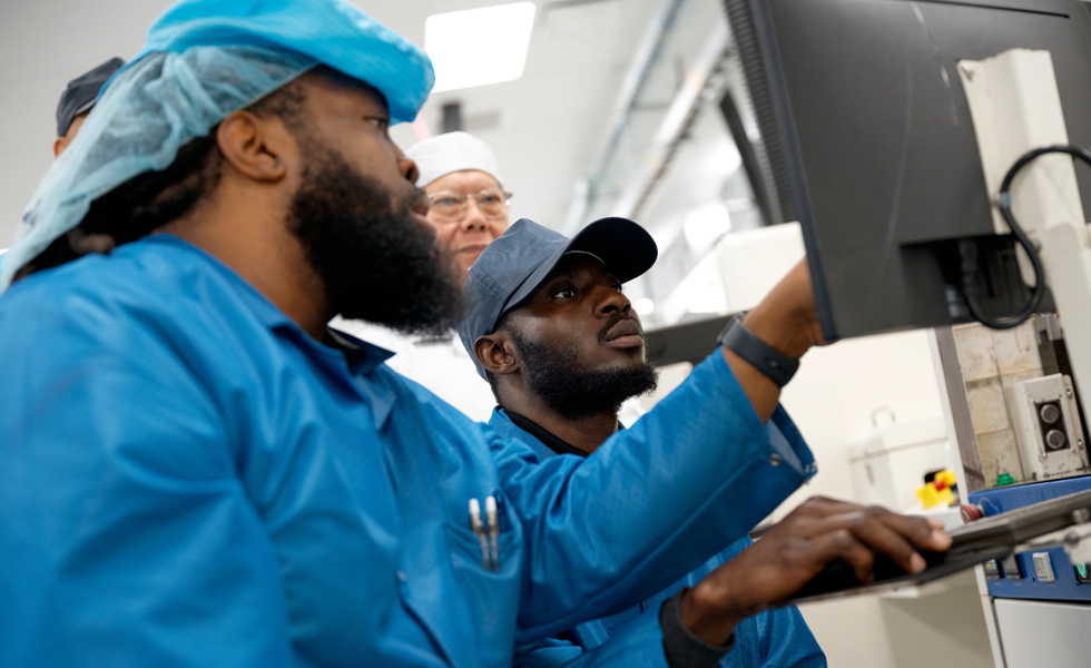 Een groep medewerkers in werkkleding werkt samen voor een monitor