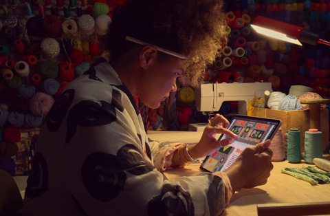 Một người ngồi ở bàn làm việc và đang thao tác hai ngón tay trên màn hình iPad để phóng to hình ảnh.